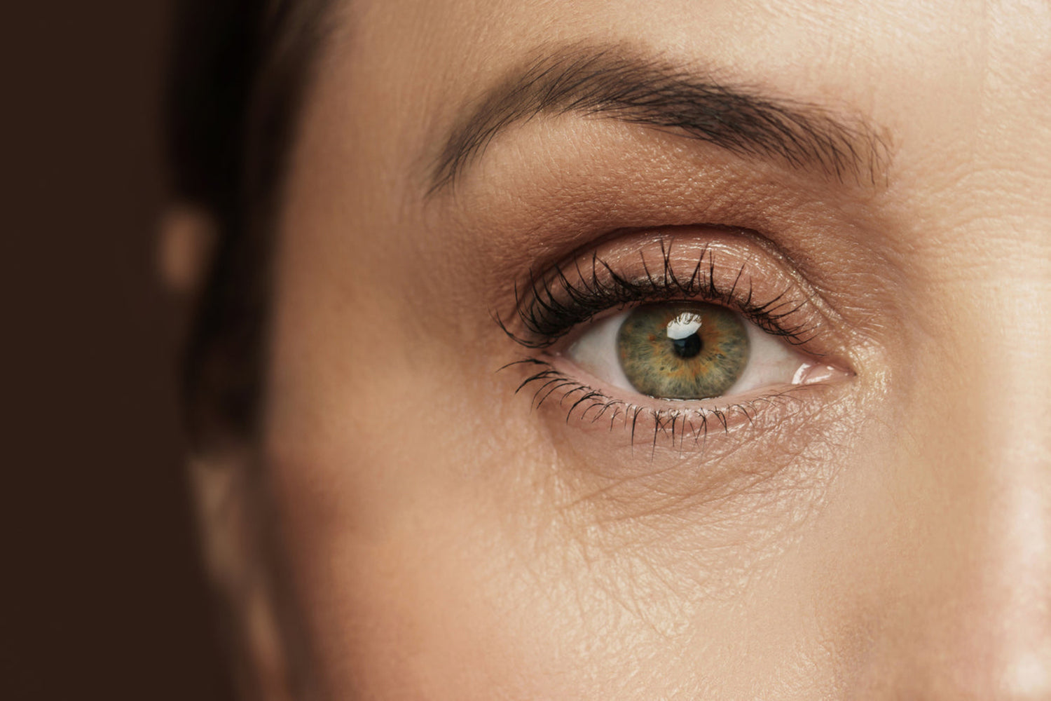 Close-up of a person's eye with a brown background